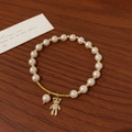 Detail of pearl bracelet with golden bear charm and zircon pendant on wooden surface - Bear Charm Style