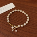 Detailed macro view of an elegant pearl bracelet with a golden zircon cherry blossom pendant - Cherry Pendant