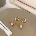 Close-up of elegant gold long tassel earrings with zircon orb on a ceramic tray - Gold White Hoop Style (A-133)