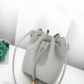 Light gray bucket bag with litchi texture and gold hardware details in a minimalist style - Gray