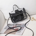 Transparent PVC crossbody bag with black inner pouch on a white sofa with newspapers - Black