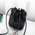Mini black bucket bag with lychee texture and gold hardware on white surface - Black