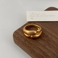 Macro detail of matte gold crossover ring featuring thick rounded ends on wooden stand - Matte Gold Irregular Staggered Overlay Ring