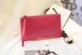 Vista dettagliata della trama a coccodrillo rosa su una pochette piatta con cinturino da polso - Rosso rosa