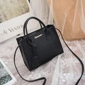 Litchi pattern black handbag with gold logo and detachable shoulder strap on a table - Black
