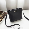 Elegant black lychee leather crossbody bag with gold metal logo on a magazine background - Black