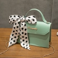 Mint green leather kelly bag with polka dot scarf and gold chain strap on wooden table - Green