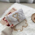 White quilted shoulder bag with golden heart buckle and tassel on plush background - Off-white