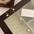 Primer plano de un collar dorado con colgantes de corazón sobre cristal vintage - Colgante de corazón / Dorado