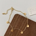 Primer plano de una pulsera de cadena dorada con cinco dijes de discos pulidos sobre madera - Disco redondo dorado (D-82)