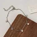 Detalle de una tobillera plateada con dijes de corazón y cierre de langosta ajustable - Corazón plateado (D-82)