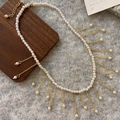 Detail of elegant pearl necklace with gold fringe tassels on a soft textured background - Bright Luster Pearl Tassel Necklace