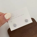 Macro detail of silver round pave-set cubic zirconia stud earrings on display card - Silver