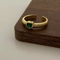 Dettaglio dell'anello dorato con texture a coste e zircone verde a cuore - Anello d'oro con zircone verde