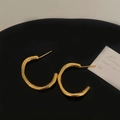 Macro view of gold irregular twisted hoop earrings on a black tray with a card - Irregular Twisted Gold Hoop