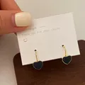 Elegante goldfarbene Creolen mit schwarzen Herzanhängern in Marmoroptik auf Karte - Schwarze Herz-Ohrringe