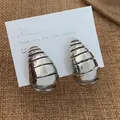 Gros plan sur boucles d'oreilles spirales argentées avec rainures texturées - Argenté