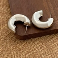 Dettaglio di orecchini a cerchio spessi a C in argento lucido su sfondo in legno rustico - Orecchini a C da 3cm Argento