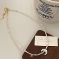 Detail of crescent moon pendant and mother-of-pearl bead necklace on a wooden display - Pearl Shell Clip