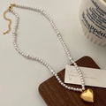 Close-up of pearl necklace with gold heart pendant on walnut base in elegant setting - 18# / Gold