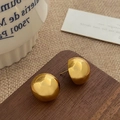 Polierte vergoldete Halbkugel-Ohrstecker auf rustikalem Holz und Stoffhintergrund - Gold