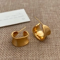 Detail of wide C-shape gold earrings with brushed texture and mirror polished interior - Gold Irregular C-Shape Style