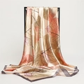 Detailed drape of champagne silk scarf with leaf patterns on elegant black frame - Gray Edge
