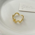 Close-up of irregular wave gold open ring with polished finish on white ceramic tray - Gold
