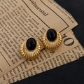 Detalle de pendientes vintage dorados con textura estriada y gema ovalada negra - Estilo de Ojo de Gato Negro Ovalado Dorado