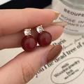 Detailed view of red pearl earrings with zircon inlay held by hand for size reference - Gold Red Pearl Earrings / Gold