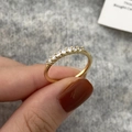 Detail of seven sparkling cubic zirconia stones set in a gold band on finger - Single Row Diamond Style / Gold