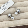 Dettaglio di orecchini di perle minimalisti con calotte in metallo argento su un vassoio - Argento