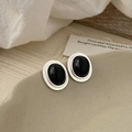 Dettaglio di orecchini ovali con pietra nera e bordo argentato su un piatto ceramico - Bordo Argento Occhio di Gatto Nero