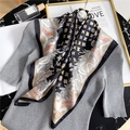 Elegant floral print silk scarf with crane pattern on a textured knit sweater - Black