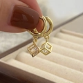 Détail de boucles d'oreilles dorées avec pendentifs cubes géométriques et pierres zircon - Pendentif Cube en Zircone Doré