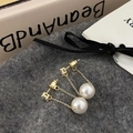 Detailed macro of gold tassel earrings with square crystal and large white round pearl - White