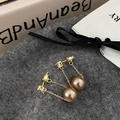 Close-up of long tassel earrings with champagne pearls and gold chain on a soft texture - Champagne