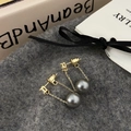 Detail of elegant gold drop earrings with grey pearls and fine chains on a soft surface - Gray