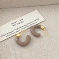 Macro shot of C-shaped hoop earrings with grey enamel finish and gold metal accents - Gray