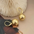 Detail von minimalistischen Goldkugel-Ohrringen auf elegantem weißem Korallenhintergrund - Goldene Runde Kugel Stil / Gold