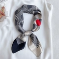 Silk-feel scarf with houndstooth, paisley and red polka dots tied as a bow over a white top - Black with Khaki Border
