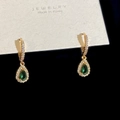 Dettaglio di orecchini dorati con pietre di smeraldo a pera e zirconi bianchi luminosi - Orecchini Pendenti con Zircone a Goccia Verde