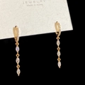 Dettaglio di orecchini a goccia dorati con tre zirconi taglio marquise e micro-pave - Orecchini Pendenti con 3 Zirconi Bianchi