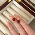 Macro view of minimalist red bead stud earrings with gold pins in a jewelry box - 6mm / 6mm Red