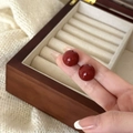 Detailed view of elegant deep red bead earrings held by hand to show compact size - 12mm / 12mm Red