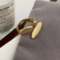 Makro-Detail des asymmetrischen vergoldeten Rings mit glattem Kiesel-Design auf Strick - Goldvergoldeter offener Ring aus Kupfer