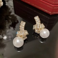 Detalle macro de pendientes de perlas doradas con nudo de circonita y acabado brillante - Pendientes Colgantes De Perla Y Circón Dorados