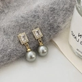 Macro detail of gold earrings featuring gray pearls and zircon stones on soft plush fabric - Gold Grey Pearl Zirconia Earrings