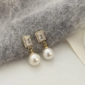 Detailed close-up of golden pearl drop earrings with sparkling rectangular zircon studs - Gold White Pearl Zirconia Earrings