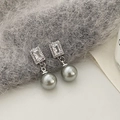 Detail shot of grey pearl drop earrings with sparkling zircons on plush grey fabric - Silver Grey Pearl Zirconia Earrings